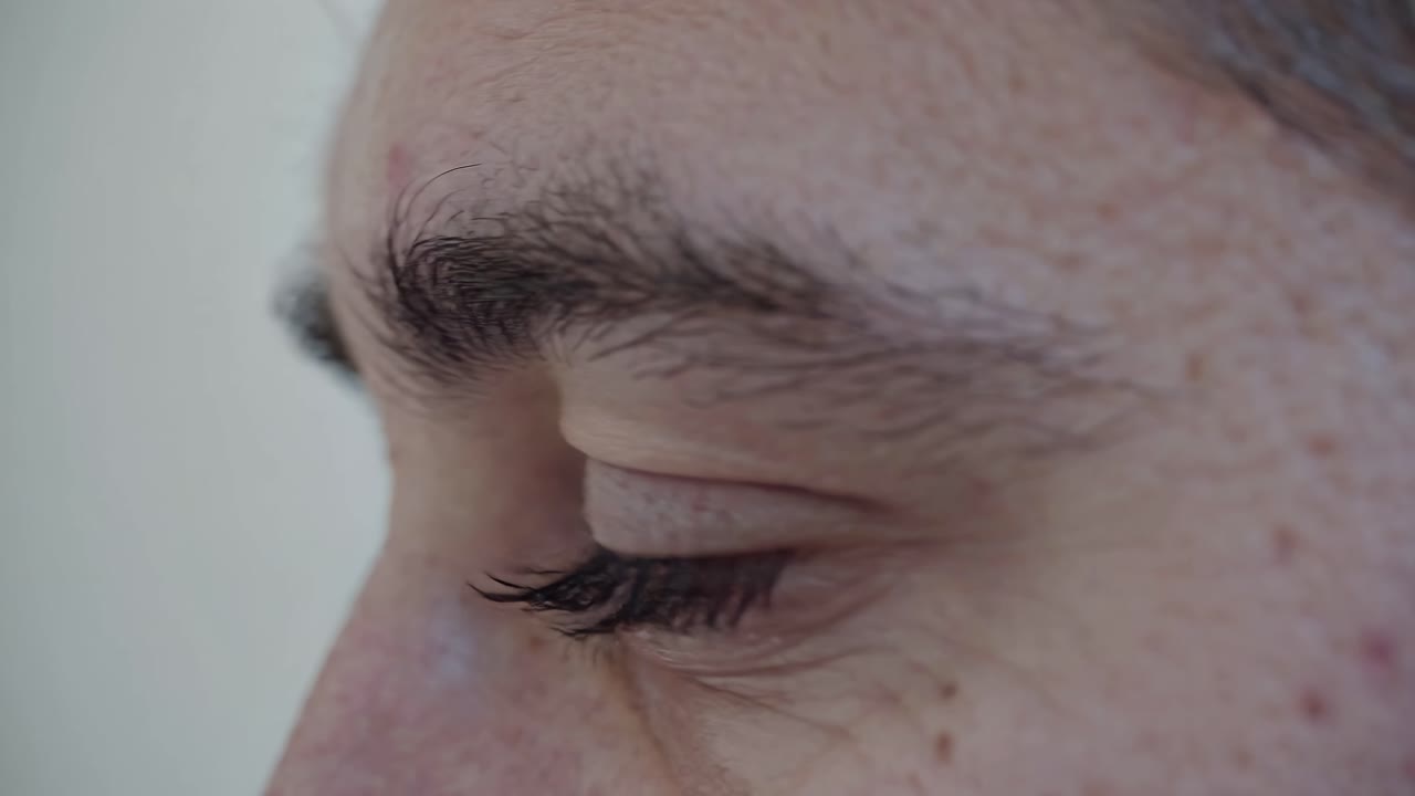 Close-up side view of a person's closed eye, focusing on eyelashes and skin texture