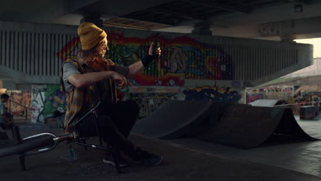 Casual-man-taking-selfie-photo-on-smartphone-at-city-skate-park-graffiti-wall.