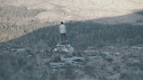 time lapse of young man standing still while shadow moves across scenic forest