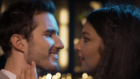 close up view of a couple celebrating new year's eve party, they get closer and kiss while smiling 2