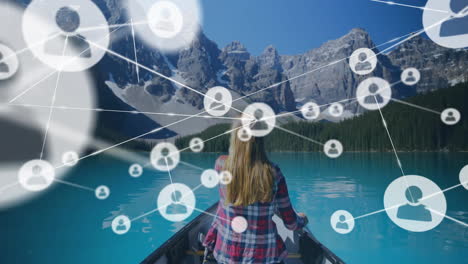 animation of network of connections with icons over caucasian woman in boat on lake in mountains