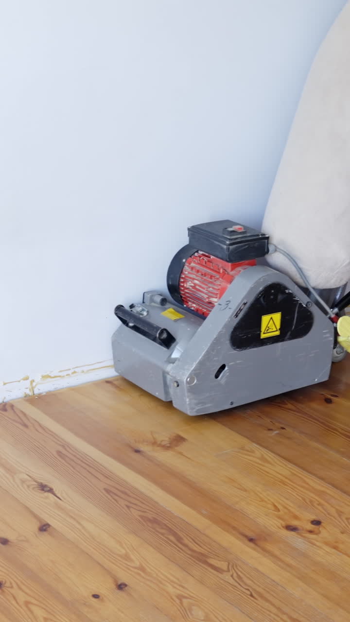 Vertical view of a sanding machine as the operator presses the start button for floor work.