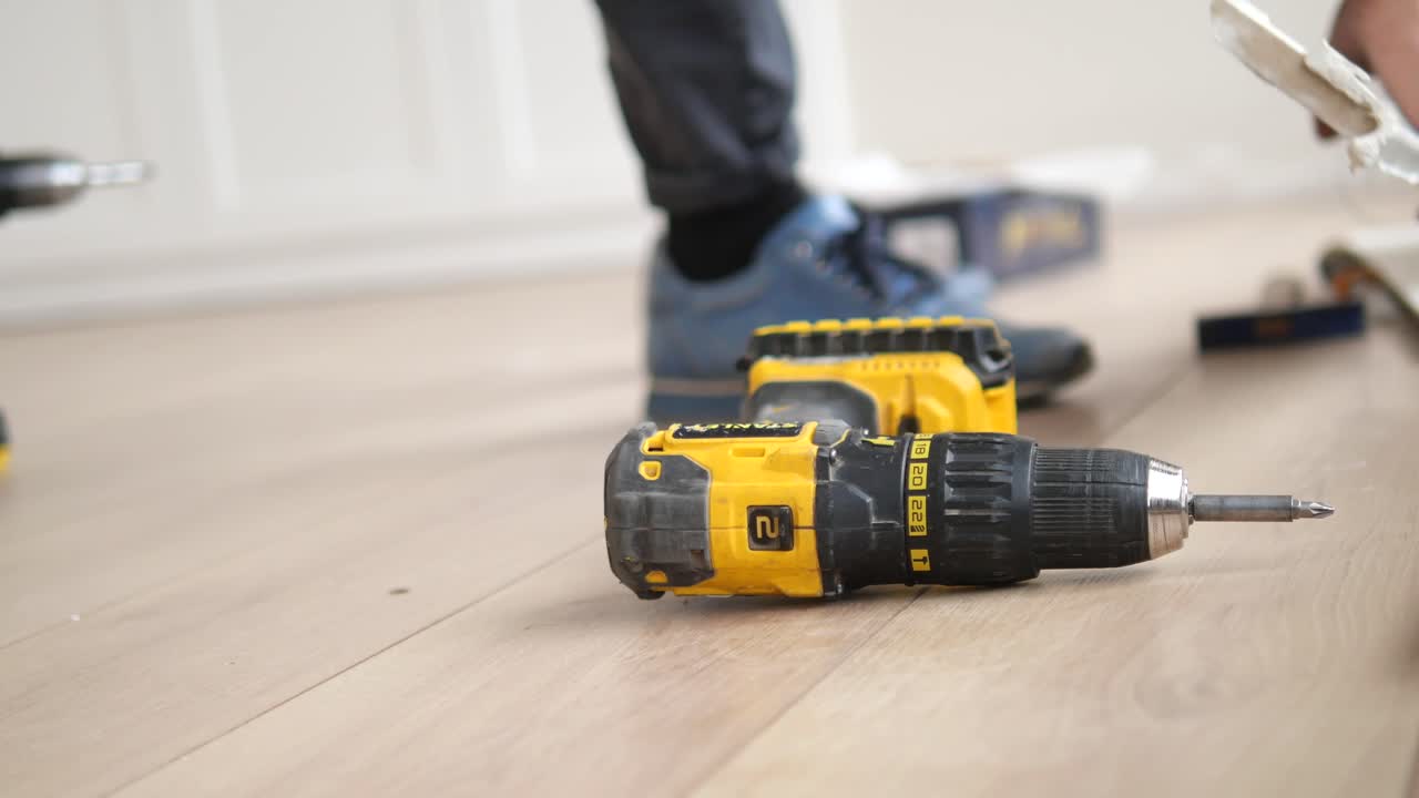 Man installing wood flooring with a cordless drill