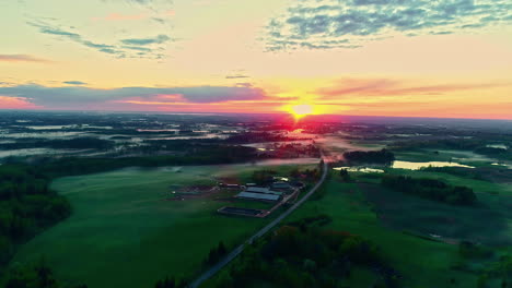 Wunderschöne-üppige-Grüne-Ländliche-Landschaft-Bei-Nebligen-Wetterbedingungen,-Roter-Sonnenaufgang-Am-Morgen,-Luftaufnahme-Eines-Lastwagens