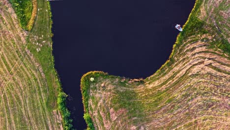 top down aerial timelapse of rowboat crossing pond and turning around
