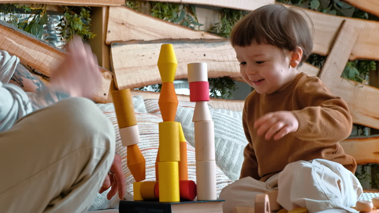 Man playing with child with colourful wooden toys on the bed