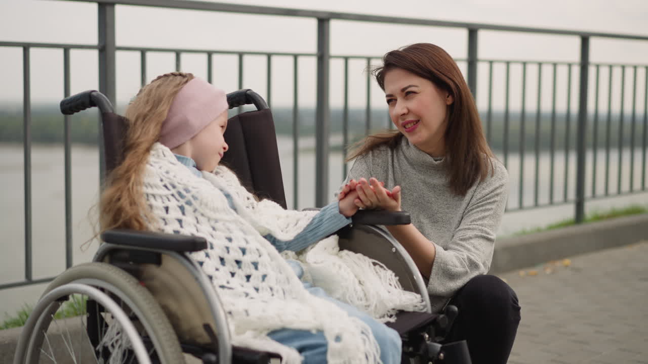 una mujer cuidadosa mira a su pequeña hija acariciando su mano suavemente