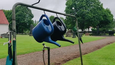 blue and green watering cans hanging from garden frame