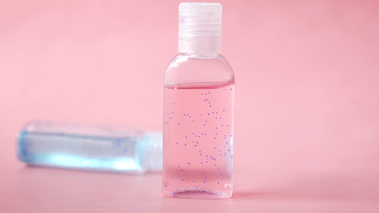 botellas de desinfectante de manos sobre un fondo rosado