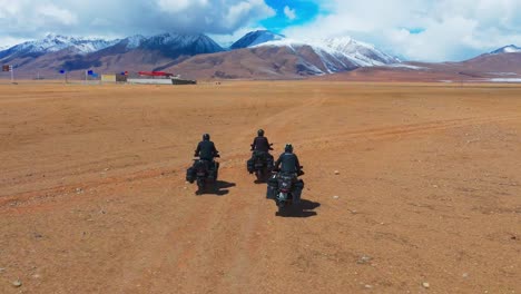 aerial drone follows group of motorbikes riding in desert, mountain landscape