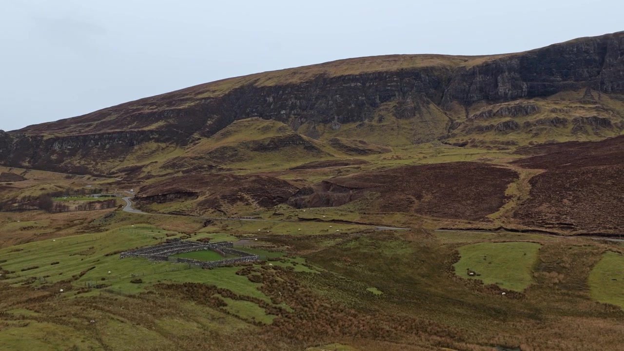 Smuk panoramaudsigt over Quiraing bjergkæden på Isle of Skye. En flok får græsser fredeligt på de grønne marker.