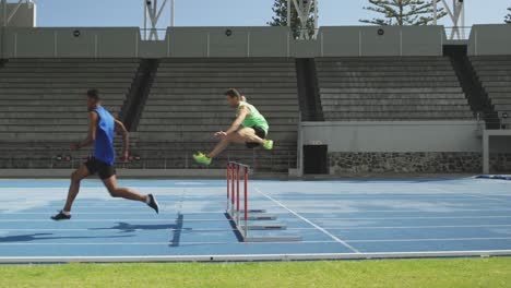 Two-athletes-doing-hurdling-in-stadium