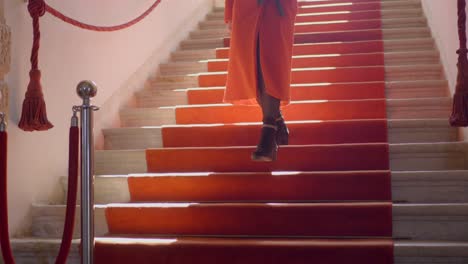 dama de clase con abrigo de invierno caminando cuidadosamente por las escaleras en la alfombra roja