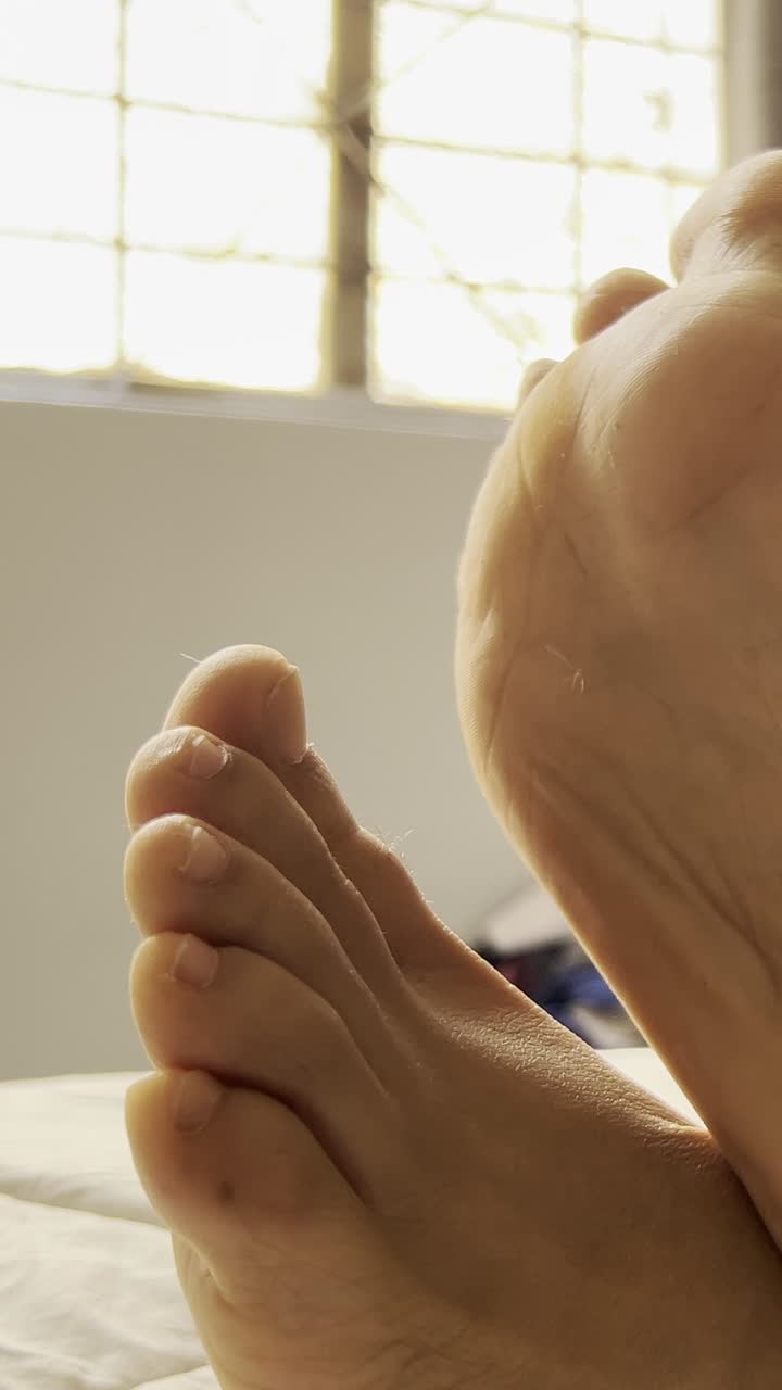 Close view of bare feet by a window, calm indoor setting