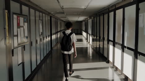 student walking down a long school hallway