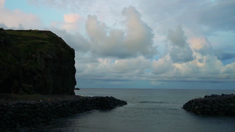 Sea-view-in-a-bay-with-rock-formations-in-the-sides-on-a-dusk-sky-with-clouds