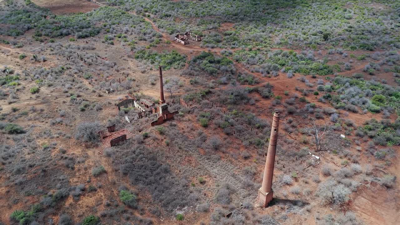 Aerial circles brick smoke stack chimneys in arid ruin of old facility
