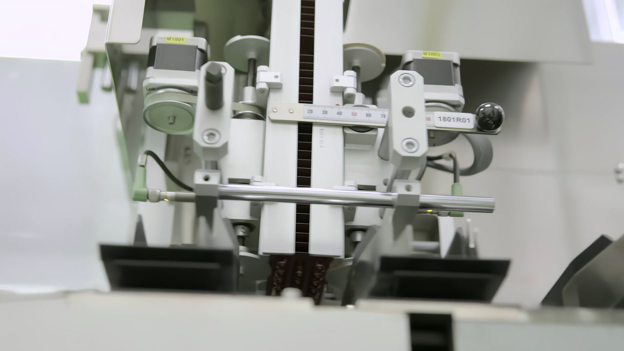 Close-up footage of a pharmaceutical machine counting blister packs before automated bottling. Precision mechanisms ensure accurate dosage and packaging in a sterile production environment.