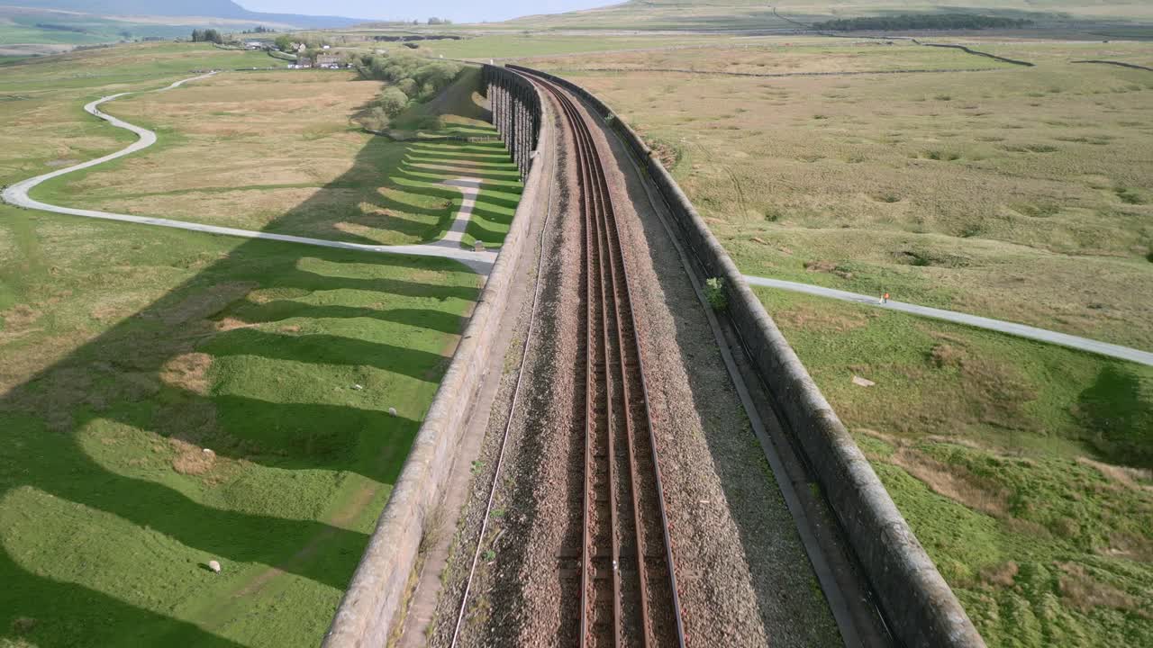 vía ferroviaria curva sobre el puente del viaducto con largas sombras de arco en la hora dorada