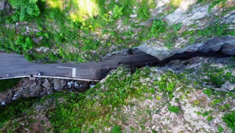 a dramatic top-down drone view of strada della forra, carved into the cliffs above lake garda—italy’s most iconic mountain drive through rock and green.