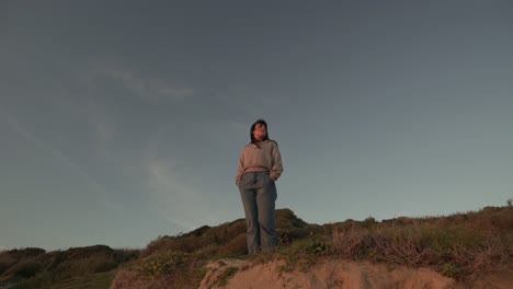 mujer viajando de pie en la colina al atardecer