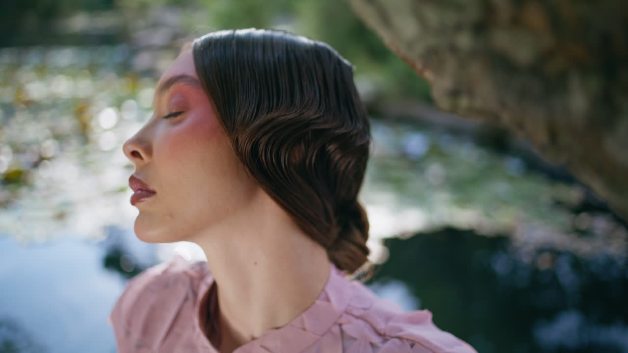 아름다운 호수에 앉아있는 카메라를 찾는 몽환적인 여성. 포즈를 취하는 소녀