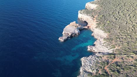 Aerial-View-Of-Crystal-clear-Blue-Water-And-Rocky-Coastline-Of-Mallorca-Island-In-Spain