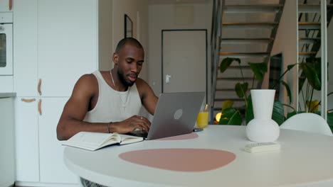 man working from home on laptop in a modern kitchen