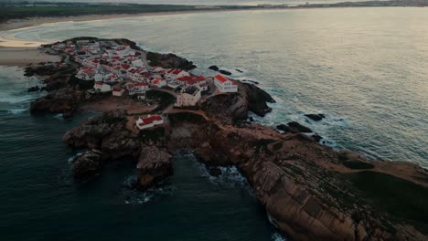 drone shot approaching balel island and revealing the sunset in the background, oeste region, portugal