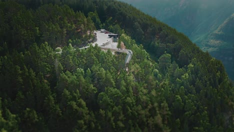 a narrow asphalt road winding uphill through the dense forest, leading to the famous stegastein viewpoint