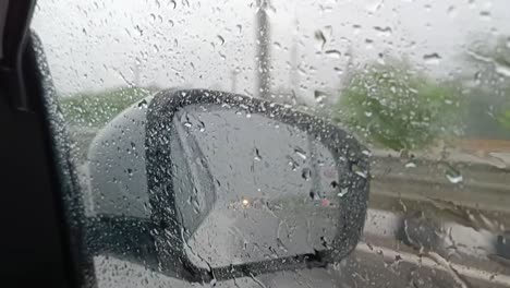 Riding-in-heavy-storm-car-mirror-reflection-of-rain-drops-on-the-city-road-driving