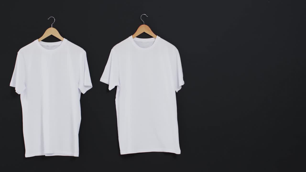 video de dos camisetas blancas en perchas y espacio de copia en fondo negro