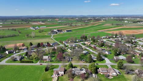 small american suburb and farm house with rural fields during sunlight in spring