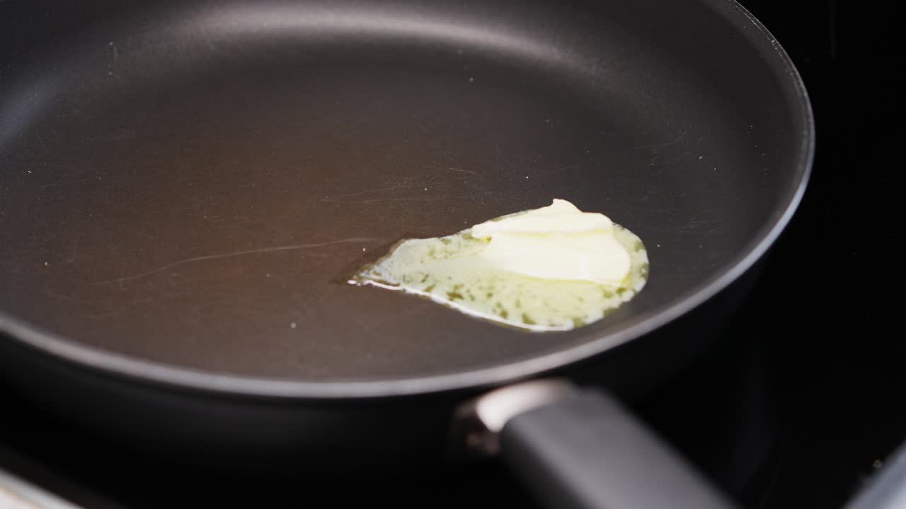 Butter melting and bubbling in hot frying pan before adding ingredients for cooking