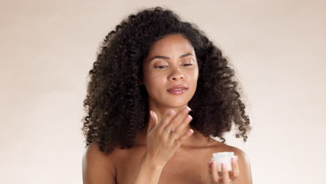 aplicar, crema para la cara y mujer negra en el estudio