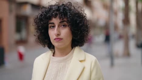 young woman standing with serious expression at street