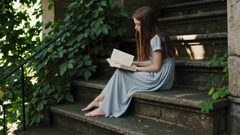 teenage girl reading a book outdoors on stone steps