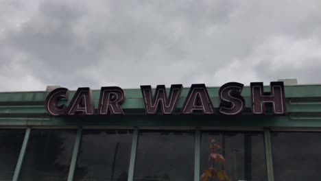 a handheld shot of gloomy skies over an abandoned neon car wash sign