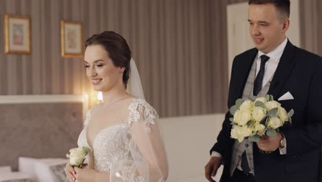 Newlyweds-young-caucasian-bride-and-groom-first-meeting-at-wedding-day,-making-a-kiss-indoors