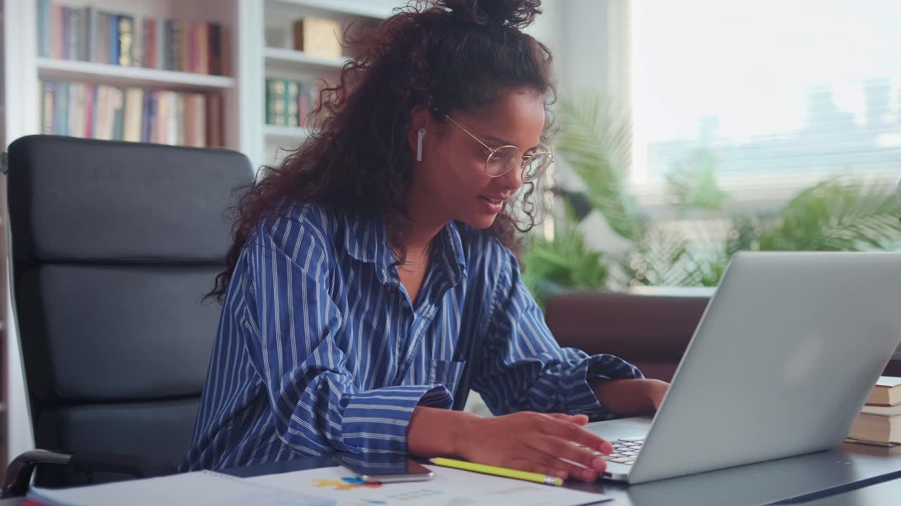 Indian woman in earphones wave greet talking on webcam conversation on laptop