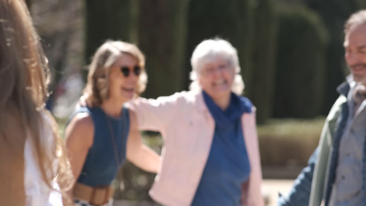 Happy mature friends embracing and walking along a park