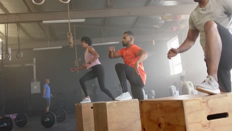 diverse group fitness class jumping onto boxes, cross training at gym, in slow motion