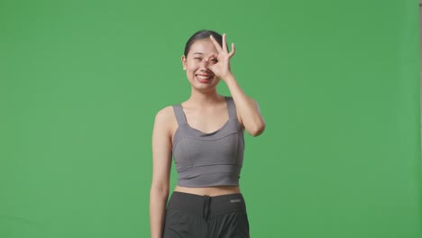 woman making ok gesture against green screen