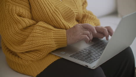 senior mature older woman typing a message on the keyboard online webinar on laptop computer remote working or social distance learning from home. 60s-80s businesswoman