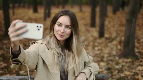 Mujer-Feliz-Sentada-En-El-Banco-Del-Parque-Y-Tomando-Un-Autorretrato