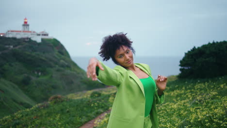 contemporary dancer moving hands gracefully on green flowers hills close up.