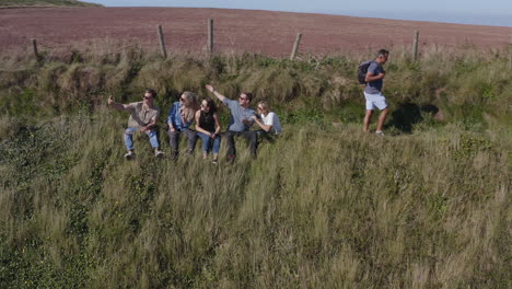 drone shot of group of friends hiking along cliffs on coastal path