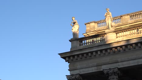 Female-statues-on-the-roof-of-the-Bordeaux-Opera-house-palace-in-France-on-a-clear-day-with-blue-sky,-Handheld-telephoto-shot