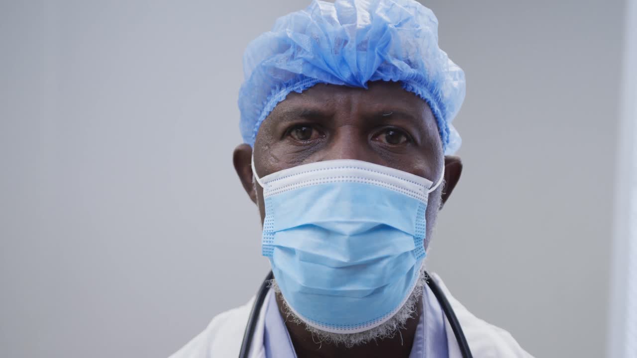 retrato de un médico afroamericano con máscara facial y gorra quirúrgica