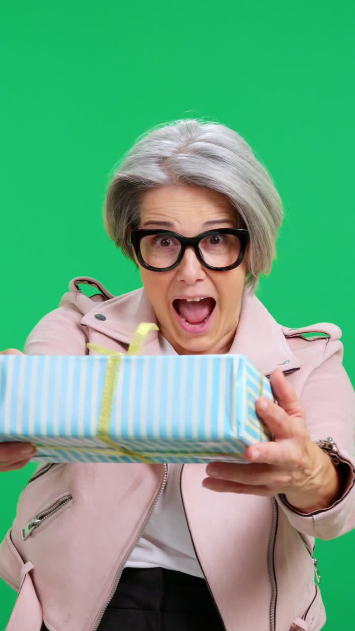 Donna di mezza età che presenta felicemente una confezione regalo incartata